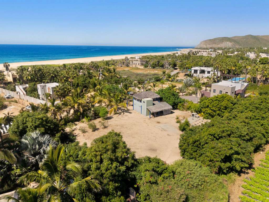 Todos Santos Pescadero Classic surf casita in El Pescadero — steps from San Pedrito. Just one row back from the beach in one of the most peaceful coastal enclaves of El Pescadero, this classic Mexican surf casita sits on an oversized ½+ acre lot surrounded by palms, mature gardens, and ocean air. A walled and gated sanctuary with CFE power, active Ejido water, cistern and pump, and established fideicomiso this is the rare combination everyone waits for here. From the rustic loft bedroom and second floor, watch whales pass, follow every winter sunset, and fall asleep to Pacific surf. The existing home comes with completed architectural remodeling plans for a two-story, two-bedroom home. The existing home has a loft living area under the palapa roof, two baths, and a garage. This land is ideal for those who want to grow food, build a food forest, practice permaculture, or simply live seasonally outdoors. This corner of San Pedrito has become a small, quiet, like-minded community with slow mornings, surf walks, starry nights, supportive neighbors, and true Baja time.Walk to the world-class San Pedrito surf break. Ride a bike to farm stands, coffee, mezcal bars, and small eco-tourism operations. It is still the old Baja feeling but with the infrastructure that makes living easy.A rare chance to own a spacious coastal property in one of Baja's most effortlessly soulful places, an opportunity for people to build a different life. – Casa Las Flores, Pacific, Pacific, BS